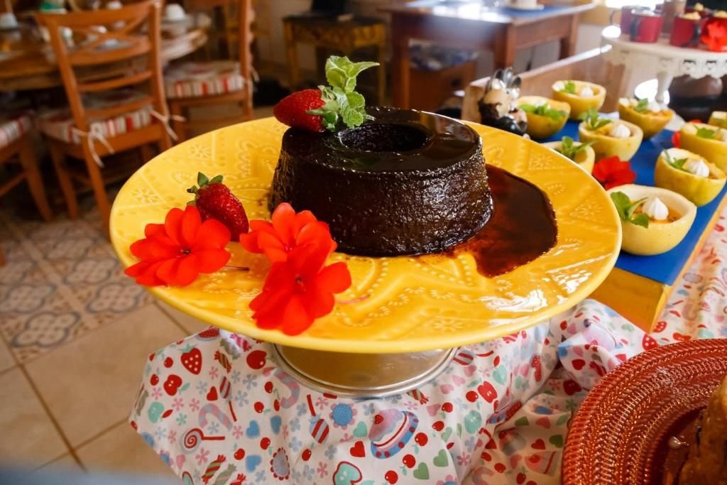 Pudim de chocolate decorado com morangos e flores em prato amarelo