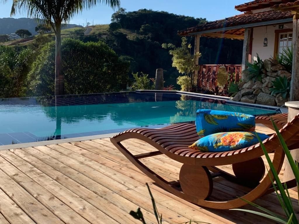 Deck de madeira com espreguiçadeira à beira da piscina de borda infinita, com a serra ao fundo